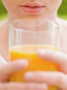 Extreme close up of young woman holding a glass of orange juice