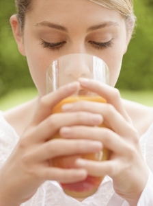 Close up of a young woman drinking and holding a glass of orange juice