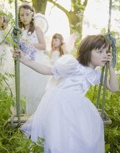 Portrait of a young girl in a fairy costume sitting on a swing