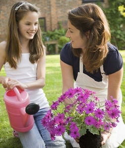 Mother and daughter kneeling in the garden tending plants and smiling
