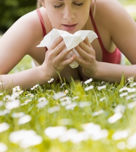 Young woman lying on stomach on the grass sneezing