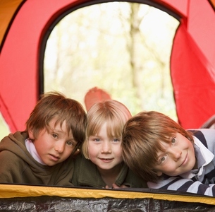 Portrait of three children lying in a tent