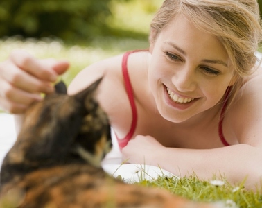 Young woman lying on the grass caressing a cat
