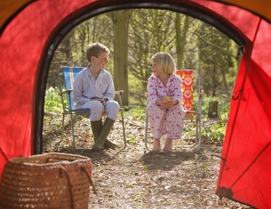 Portrait of boy and girl sitting outside tent entrance