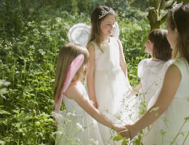 Young girls in fancy dress holding hands in a garden