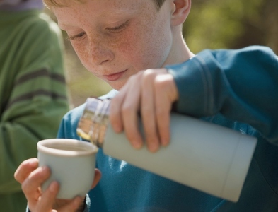 Close up of young boy pouring water from insulated flask
