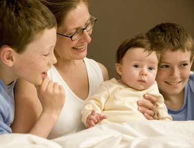 Portrait of a woman in bed with her children and newborn baby
