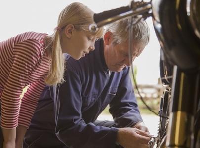 Young girl helping grandfather repairing motorbike