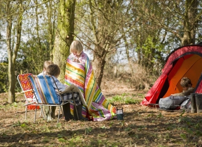 Young girl wrapped in a blanket interacting with friends at campsite