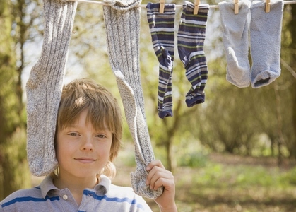 Close up of young boy standing between socks hanging from clothes line