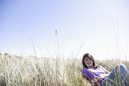 Young woman lying down on a field smiling