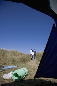 Back of three people walking with tent opening