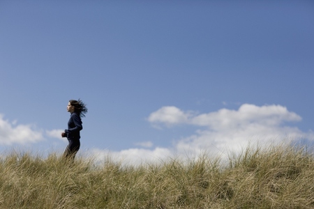 Young woman running through sand dunes