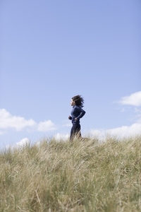 Young woman running through sand dunes