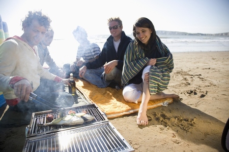 Friends sitting around a barbeque on the beach
