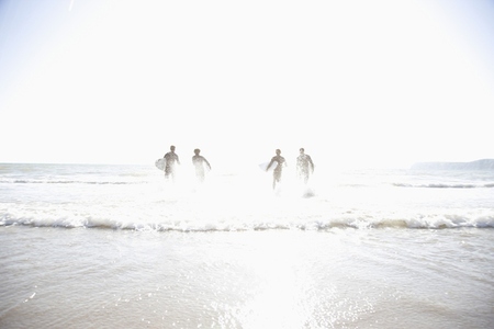 Silhouette of surfers running in the sea