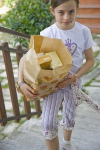 Young girl walking up stairs carrying a brown paper bag