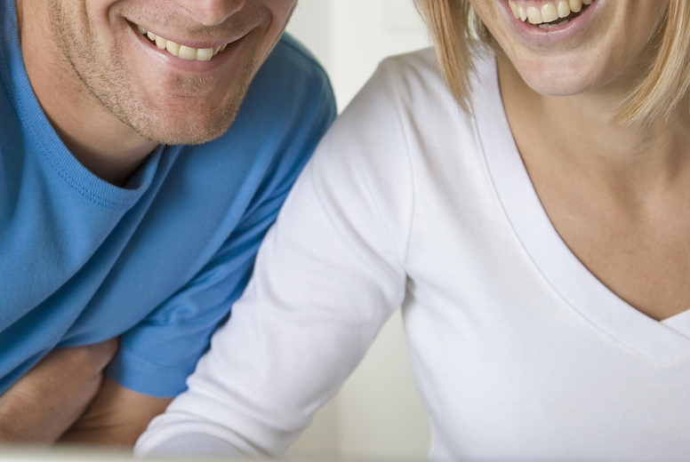 Close up of a young couple laughing and looking at laptop computer screen