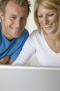 Close up of a young couple laughing and looking at laptop computer screen