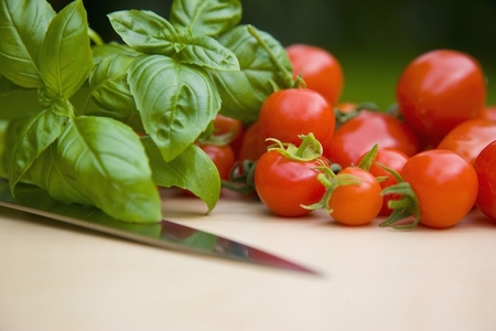 Close up of cherry tomatoes basil leaves and a knife blade
