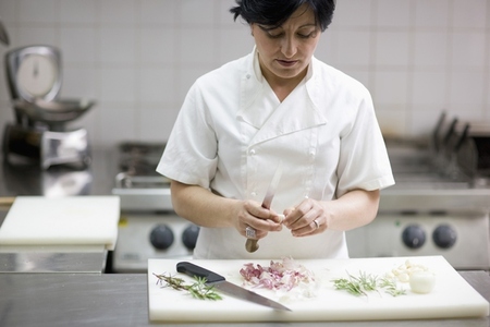Woman chef peeling garlic with a knife