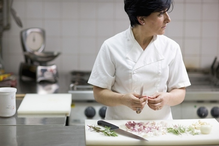 Woman chef peeling garlic with a knife looking to one side