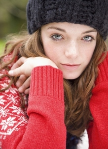 Close up of teenaged girl wearing woolly hat with face resting on hands