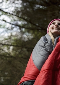 Standing teenaged girl wrapped in a sleeping bag looking up and smiling