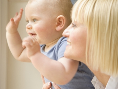 Close up of a baby waving his arms with his mother holding him