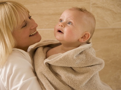Close up of baby wrapped in  a towel with his mother holding him