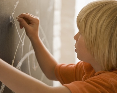 Young boy writing on a blackboard