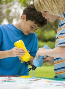 Two young boy squeezing liquid color paint out of bottles