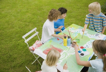 Children sitting and painting in the garden