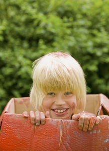 Close up of a young blonde boy in a cardboard box smiling