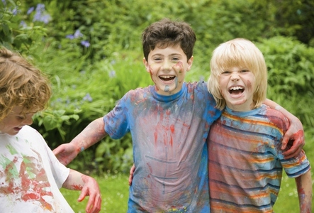 Young boys covered in watercolor paint laughing in a garden