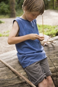 Young boy tying a knot with a string around a stone
