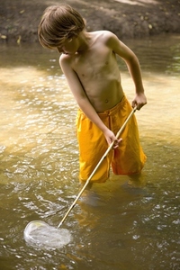 Young boy fishing in a river with fishing net