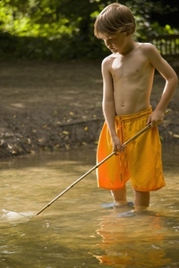 Young boy fishing in a river with fishing net