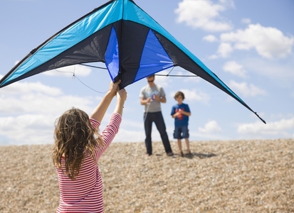 Back view of young girl standing on a beach holding a kite