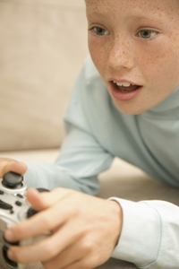 Close up of a young boy playing and holding a video game control