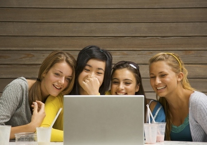 Teenage girls using laptop computer laughing