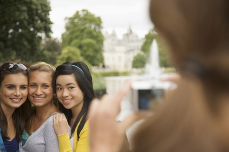 Back view of a woman taking photograph of three teenaged girls