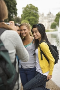 Back view of woman taking photograph of three teenaged girls