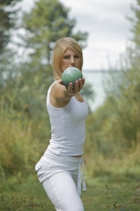 Young woman stretching and balancing a sphere in one hand