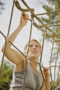 Young woman at obstacle course climbing a cargo net