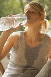 Close up of a young woman drinking water from a bottle with her eyes closed