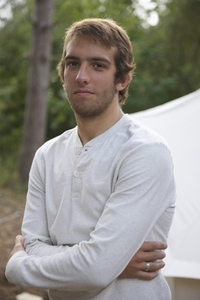 Young man standing by a tent with his arms crossed