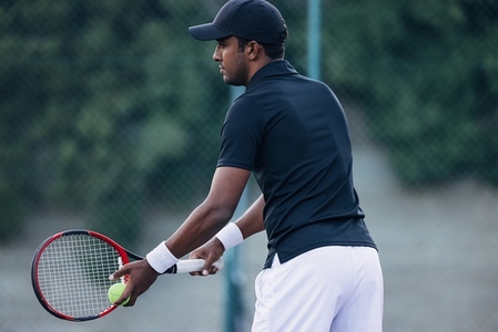 Side view of a tennis player preparing to hit the serve during a match outdoors