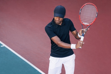 Professional tennis player in a cap holding a racket on a hard court