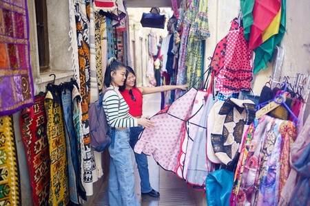 Two young Chinese women looking at typical clothes in the typical handicraft